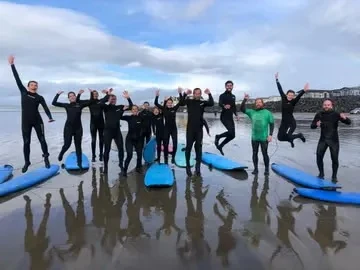 Surf Ireland friends jumping beside their boards on the beach.
