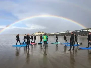 The surf group and their boards beneath a rainbow.
