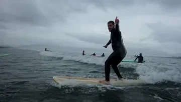 A surfer standing on a board on a small wave.